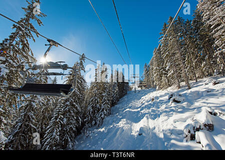 Vista panoramica di una coperta di neve catena montuosa alpina mentre si è in viaggio sulla seggiovia ski lift in presenza di luce solare Foto Stock