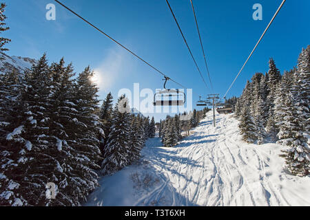 Vista panoramica di una coperta di neve catena montuosa alpina mentre si è in viaggio sulla seggiovia ski lift in presenza di luce solare Foto Stock