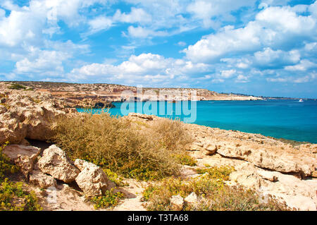 Vista della Laguna Blue Bay nei pressi di Cape Greco, Cipro. Costa di roccia nei pressi di verde profondo trasparenti acque azzurre, diverse le barche in acqua. Incredibile il cloud Foto Stock