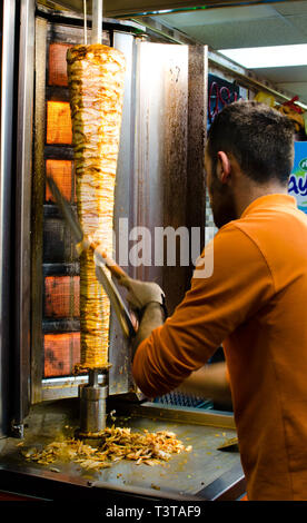 Istanbul, Turchia, Marzo 08, 2019: lavoratore presso un ristorante fast food il taglio di Döner Kebab sulla rotazione spiedo verticale, tradizionale cucina di strada, night shot Foto Stock