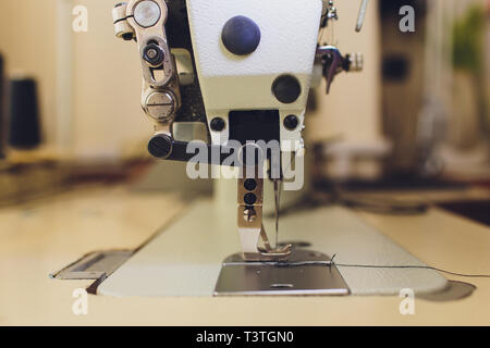 Bianco moderno macchina taglia-e-cuci, donna di colpire un pezzo di stoffa  su un piccolo tavolo Foto stock - Alamy