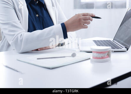 Medico operante nella luminosa studio dentistico Foto Stock