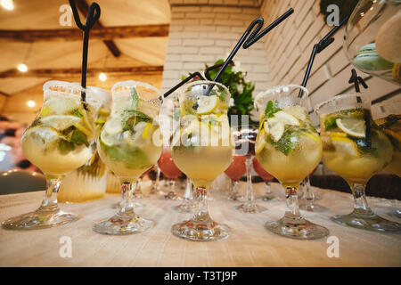 Estate Cocktail a freddo con una vasca. Diversi limonate con cubetti di ghiaccio e le fette di limone a mason jar stare su un tavolo di legno. limonata acqua Foto Stock