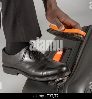 Compagnia aerea spazzolatura pilota il suo nero scarpe uniforme. Foto Stock