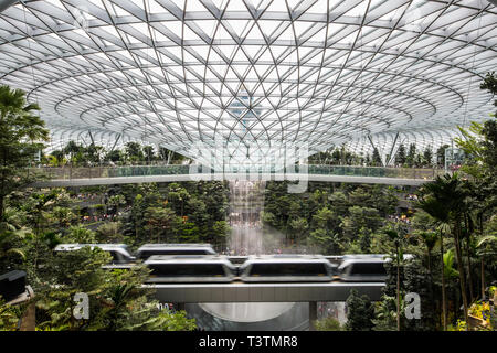 Un'ampia vista della struttura convessa che piove fino al seminterrato dell'Aeroporto Jewel Changi e della torre di controllo del traffico aereo dietro Singapore Foto Stock