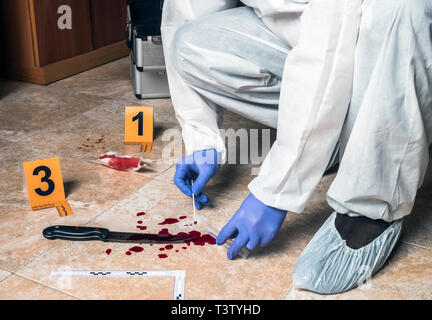 La polizia di esperti prende il campione di sangue da un coltello di sangue sulla scena di un crimine, immagine concettuale Foto Stock