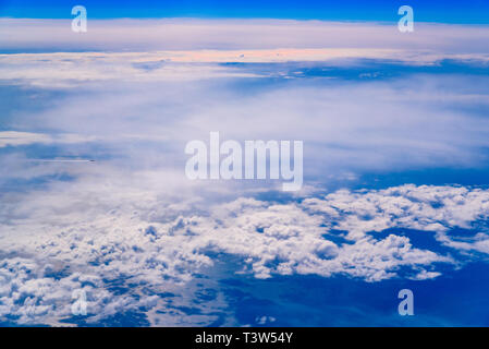 Intenso il cielo blu con nuvole bianche ed il piano che la attraversano, visto da sopra in un altro piano. Foto Stock