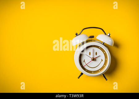 Piccolo orologio bianco posto su uno sfondo giallo Foto Stock