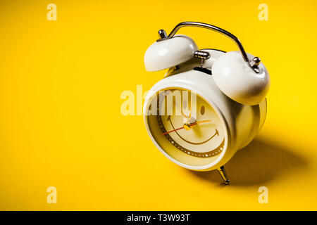 Piccolo orologio bianco posto su uno sfondo giallo Foto Stock