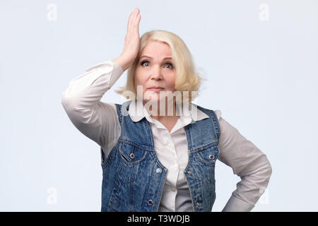 Dimentico anziani donna bionda di graffiare la sua testa Foto Stock