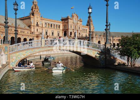 Persone imbarcazioni a remi sul fossato della storica Plaza de Espana in Siviglia, in Spagna il 3 aprile 2019. È stato costruito per il 1929 esposizione Ibero-americana. Foto Stock