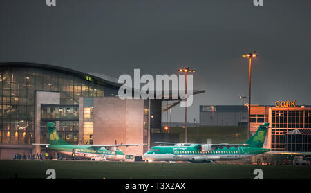 Aeroporto di Cork, Cork, Irlanda. Il 12 aprile, 2019. Passeggeri a bordo di un Aer Lingus piano regionale legato per Birmingham mentre un altro si prepara a taxii sulla pista per un volo a Edimburgo. Aer Lingus Regional sono azionati da aria Stobart il cui equipaggio di cabina hanno votato a favore dell'azione industriale e che possono mettere a terra gli operatori irlandesi voli per il Regno Unito per le vacanze di Pasqua. Credito: David Creedon/Alamy Live News Foto Stock