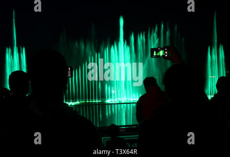 La gente del posto e turisti guarda il laser e spettacolo della fontana musicale sulle rive del Lago Dal a Srinagar, in indiano Kashmir amministrato il 10 aprile 2019. La mostra inaugurale del laser fontana e spettacolo musicale ha attratto molti spettatori per la sua miscela di luce, musica e acqua, sulla riva del pittoresco dal lago. Decimo Apr, 2019. La fontana musicale quotidiani spettacoli serali mirano a fornire intrattenimento per la gente del posto oltre a promuovere il turismo e la proiezione di un'immagine positiva del Kashmir Credito: Muzamil Mattoo/IMAGESLIVE/ZUMA filo/Alamy Live News Foto Stock