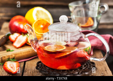 Frutta tè rosso con arance e bacche sul tavolo di legno Foto Stock