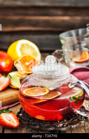 Frutta tè rosso con arance e bacche sul tavolo di legno Foto Stock