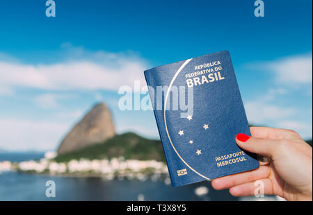 Mano azienda brasiliana con passaporto SugarLoaf Mountain a Rio de Janeiro in Brasile in background - composito digitale Foto Stock