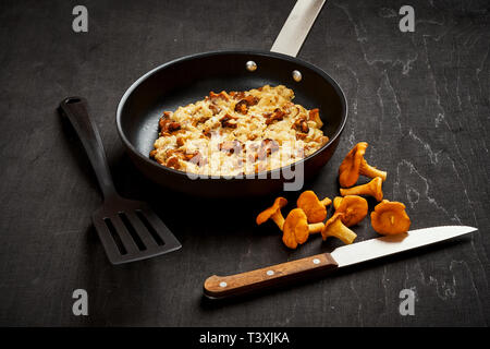 Deliziose uova strapazzate con i finferli direttamente dalla foresta in una teglia su una cucina in legno tabella Foto Stock