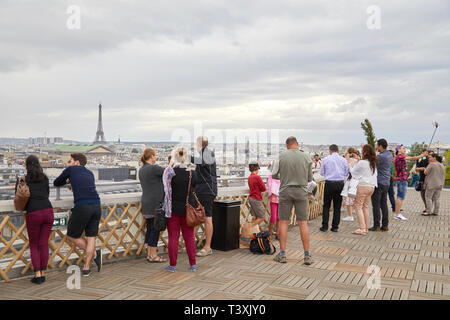 Parigi, Francia - 22 luglio 2017: Cittadini e turisti alla ricerca di tetti di Parigi la visualizzazione e la Torre Eiffel dalla Galeries Lafayette terrazzo in un giorno nuvoloso in Foto Stock