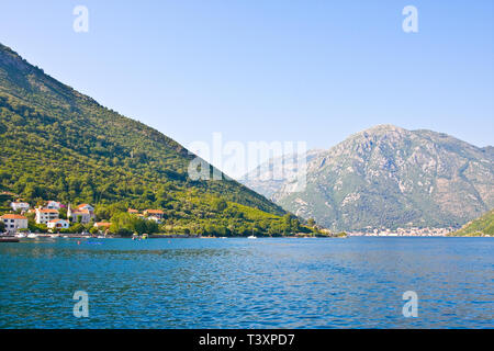 Parte più stretta della baia di Cattaro, lo stretto di Verige. Chiesa e case con tetto rosso titolo. Kamenari. Montenegro Foto Stock