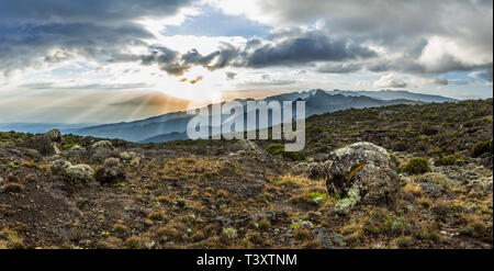 Vista panoramica del tramonto sul Monte Meru in Tanzania preso dalla grotta Shira camp su Machame route di Kilimanjaro. Sunray scoppiare attraverso le nuvole Foto Stock