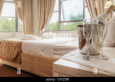 Champagne e bicchieri da letto in camera di albergo Foto Stock