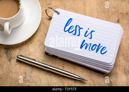 Meno è meglio - scrittura su una pila di schede indice con una tazza di caffè e una penna, minimalismo concept Foto Stock