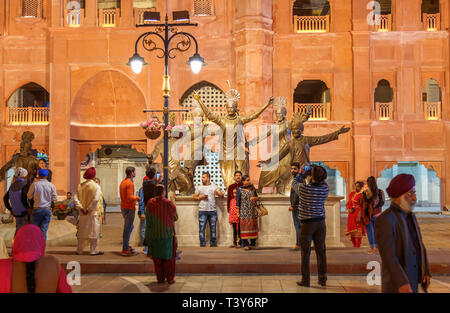 La popolazione locale che si diverte in Amritsar centro città di notte in posa e scattare foto e selfies accanto a grandi statue stradale Foto Stock