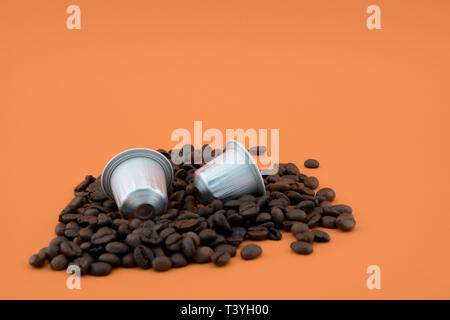 Caffè Espresso capsule o cialde di caffè in chicchi di caffè, sfondo arancione. Capsule per macchina da caffè. Foto Stock