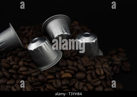 Caffè Espresso capsule o cialde di caffè in chicchi di caffè, sfondo nero. Capsule per macchina da caffè. Foto Stock
