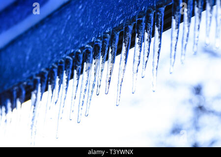 Sfondo Inverno con cristallo ghiaccioli e la caduta di gocce di lucido. Icicle sulla bella texture brillanti. Stalattiti di fusione durante la primavera. Foto Stock