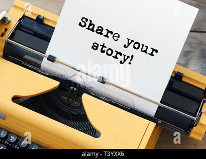 Condividete la vostra storia! Parole scritte sulla macchina da scrivere di colore giallo Foto Stock