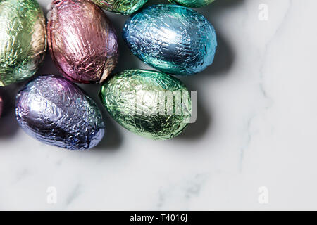 Uovo di Pasqua tratta di cioccolato avvolto in lucido foglio colorato su Sfondo marmo Foto Stock