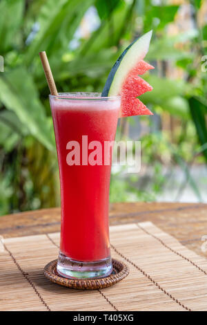 Anguria succo in un bicchiere alto con bambù paglia. Foto Stock