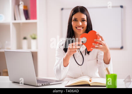 Giovane medico nel suo ufficio a parlare di salute del cuore. Foto Stock