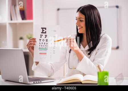 Giovane medico è in possesso degli occhi prova di esame nel suo ufficio. Foto Stock