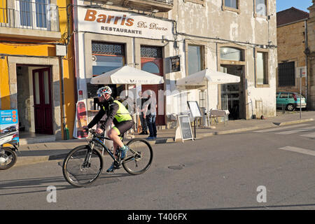 Uomo che indossa la lycra, casco occhiali ciclista in bicicletta lungo una strada passato Barris do Douro restaurante nella città di Porto Portogallo UE KATHY DE Foto Stock