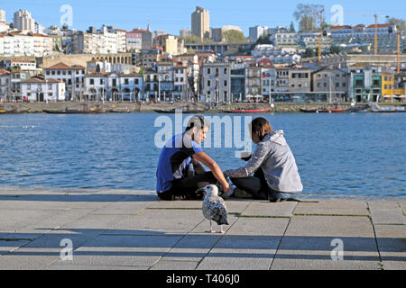 Una giovane coppia seduta che mangiano insieme sulla banchina dal fiume Douro su una molla pomeriggio nella città di Porto, Portogallo Europa KATHY DEWITT Foto Stock