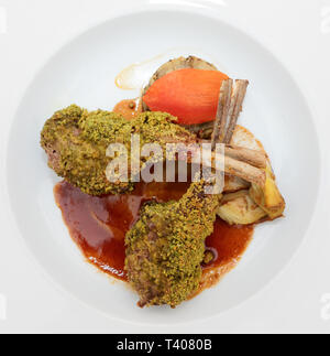 Grigliata di carré di agnello con pistacchio nella piastra, isolato su sfondo nero Foto Stock