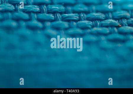 Una macro scatta di intrecciato panno blu texture. focus sul lato superiore dell'immagine. Foto Stock