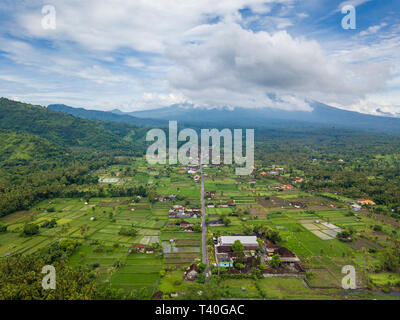 Vista aerea di Amed in Bali, Indonesia. Gunung Agung vulcano sullo sfondo, parzialmente coperto dalle nuvole. Foto Stock