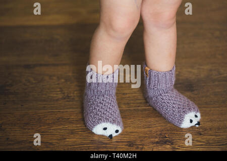 Piedi del bambino in inverno calze hedgehog su sfondo di legno Foto Stock