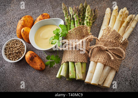 Gli ingredienti freschi per starter di asparagi con patate novelle di pepe, la maionese, il coriandolo e due fasci di bianco e asparagi verdi spears Foto Stock