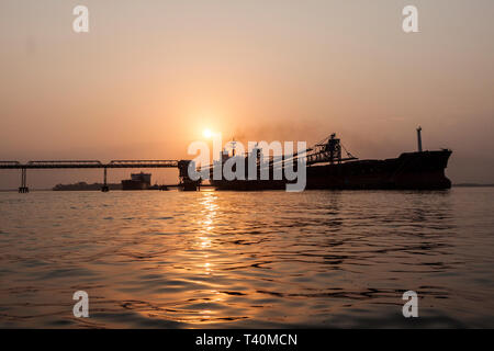 Operazioni portuali per la gestione e il trasporto di minerali di ferro all'alba e tramonto con 2 navi TSV - uno al molo di carico, uno in attesa di dock. Sierra Leone Foto Stock