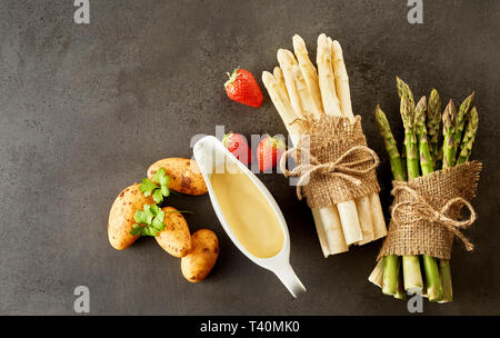 Un assortimento di ingredienti per una molla gourmet antipasto con due fasci di verde e asparagi bianchi spears, maionese, fragole e baby di patate novelle Foto Stock