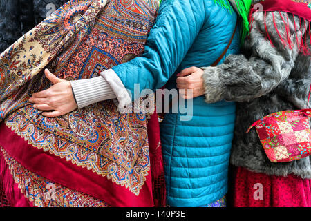 I partecipanti del festival tradizionale in diversi costumi etnografici pongono in primavera per un fotografo nella capitale lettone Riga Foto Stock