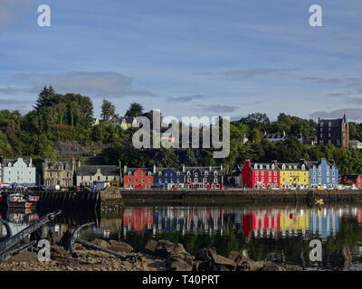 La vista sul porto e le case colorate di Tobermory con le loro riflessioni sulla superficie dell'acqua sull'Isola di Mull in Scozia Foto Stock