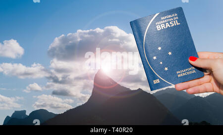 Mano che tiene il passaporto brasiliano con la statua del Cristo Redentore a Rio de Janeiro in Brasile in background - composito digitale Foto Stock