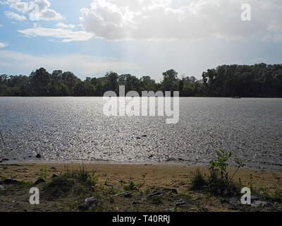 La pioggia con il sole sopra il fiume. Resto in un giorno di estate dal fiume. Estate doccia. Foto Stock