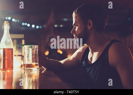 Il suo tempo per un po' di luce brew. Avvincente per la bevanda alcolica. Bevitore di uomo nel pub. Uomo bello bere birra al banco bar. L'alcol addict con boccale di birra Foto Stock