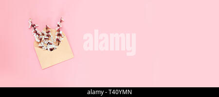Aperto craft busta di carta piena di primavera sbocciano i fiori fiori su sfondo rosa. Foto Stock